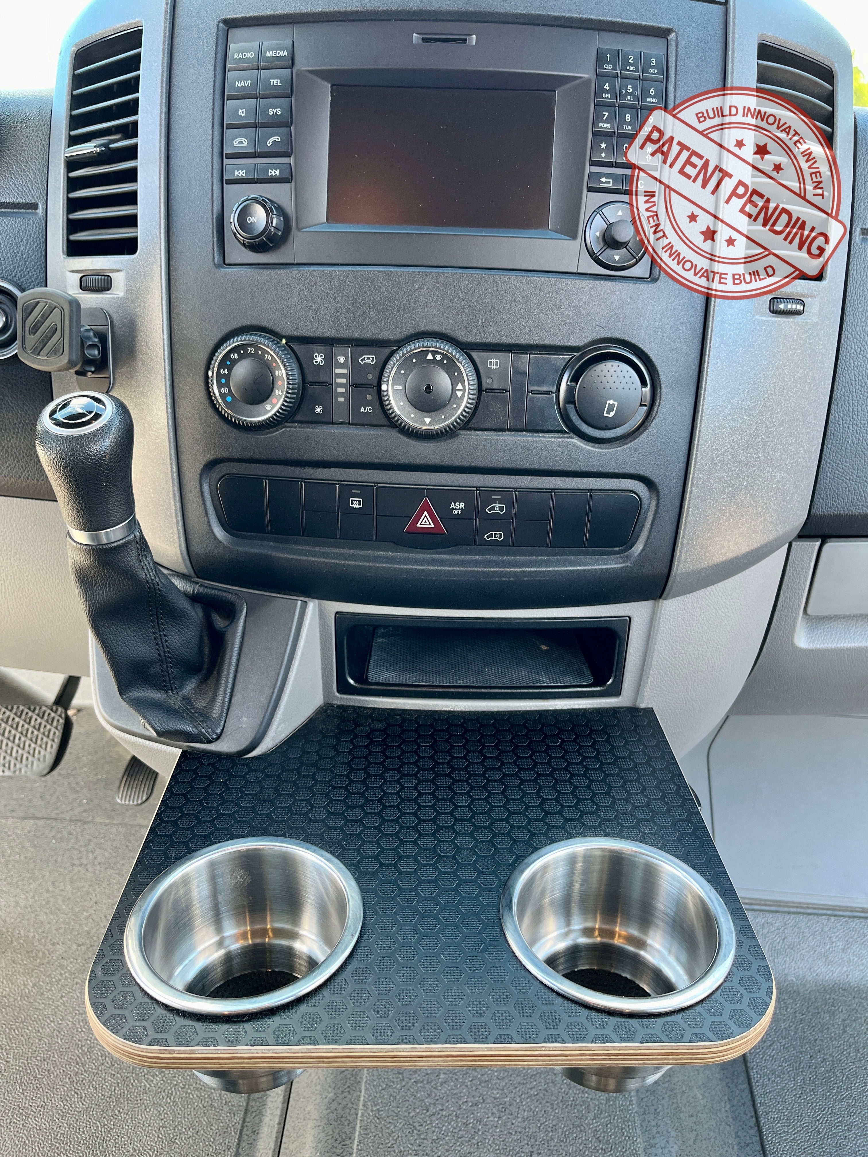 Mercedes-Benz Sprinter NCV3 06-18 Black Hex Cup Holder Snack Tray with XL Stainless Cup Holders. Converts factory sliding cup holders into a small table. Size: 12"x10.25". High pressure Black hex textured laminate top on 1/2" Baltic birch plywood base. Easy installation/removal, no vehicle modification required.