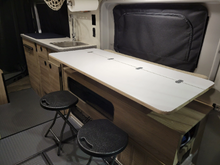 Load image into Gallery viewer, A versatile lift-up table designed for 2020-2022 Winnebago SOLIS Class B RVs, featuring a 3/4&quot; bamboo surface. It can be easily raised and lowered, providing a 48&quot; x 22.5&quot; workspace when the murphy bed is in the raised position. 
